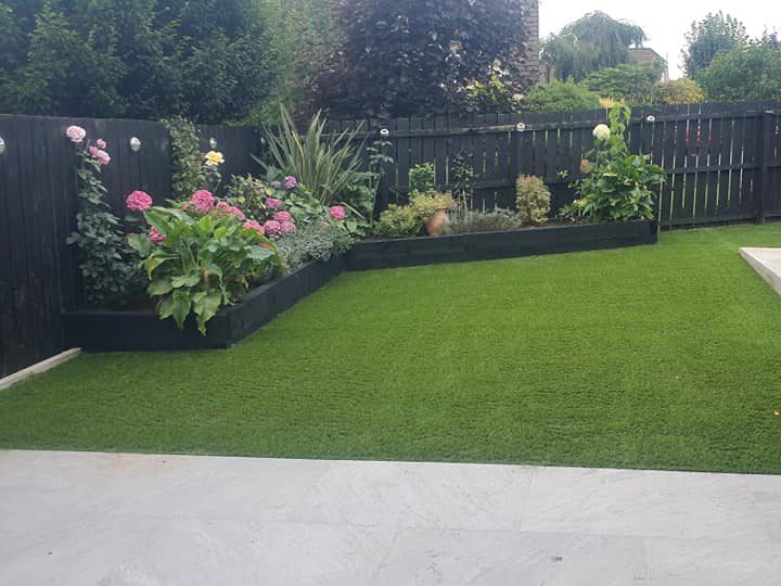 Newly paved garden with artficial grass and black wooden planters