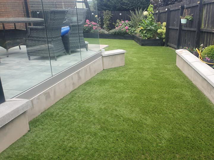 Garden with artificial grass and black wooden fence with matching planter